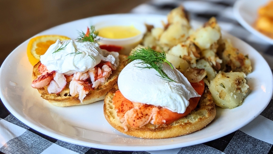 lobster Eggs Benedict with home fries on a white plate